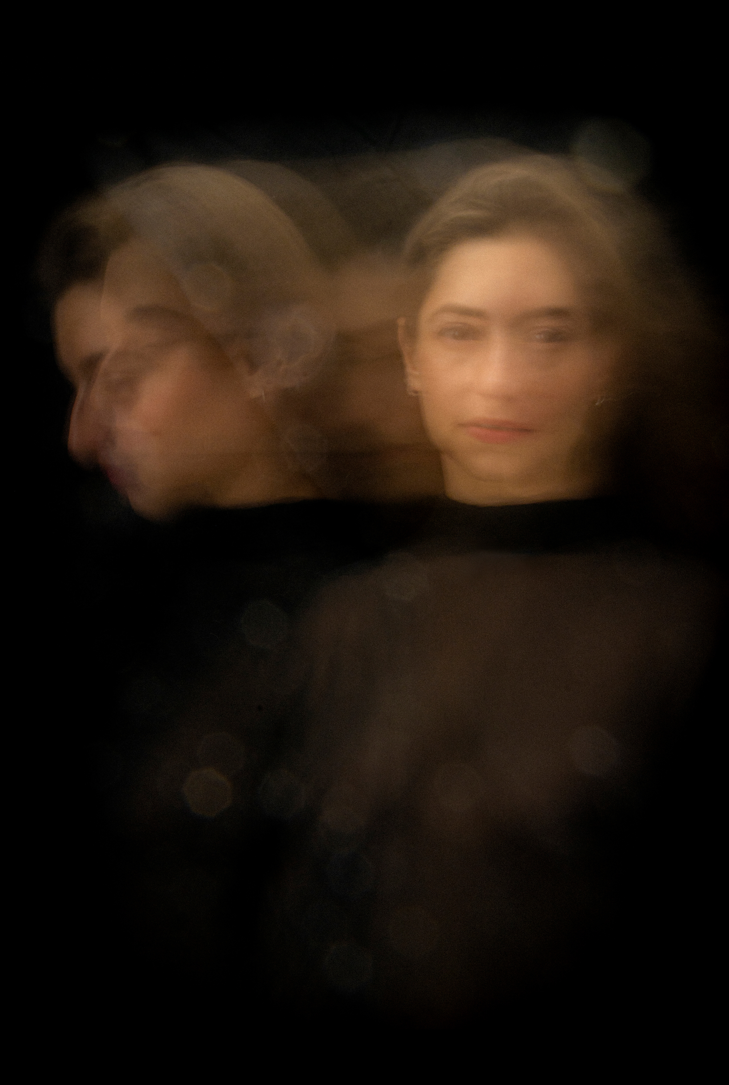 Retrato de una mujer sobre un fondo negro, realizado con un efecto de movimiento que multiplica y superpone su rostro. Una de las imágenes mira hacia la cámara, mientras otras aparecen desplazadas hacia la izquierda, algunas de perfil y otras difuminadas. La iluminación cálida crea una composición de rostros translúcidos que parecen coexistir.
